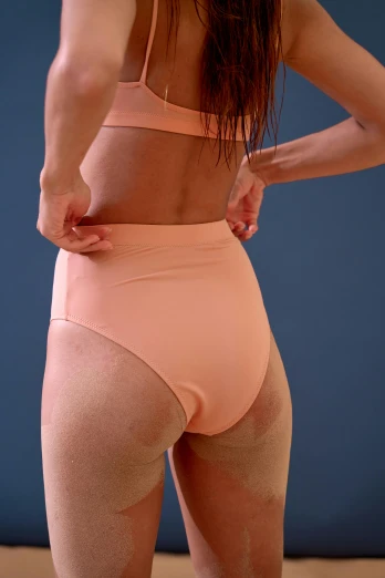 a woman in a pink underwear standing in front of a blue wall, inspired by Vanessa Beecroft, unsplash, toned orange and pastel pink, bend over posture, zoomed out view, performance