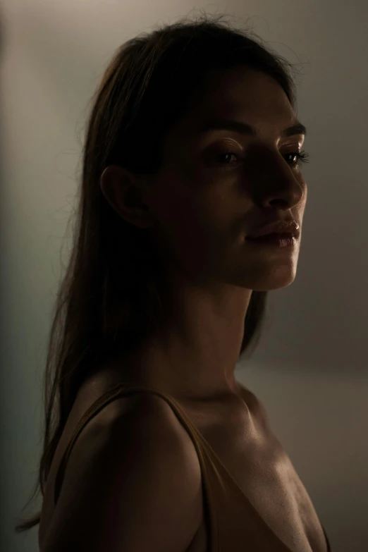 a woman standing in a dimly lit room, light and space, diffused natural skin glow, shot with sony alpha, brunette woman, mid shot
