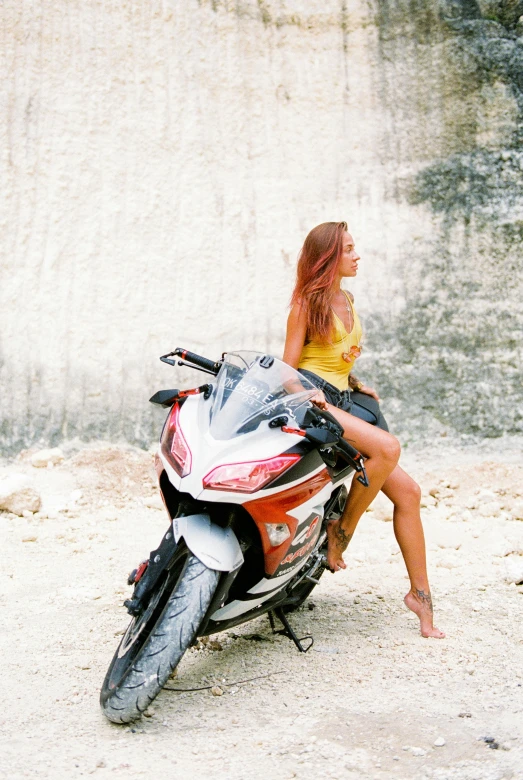 a woman sitting on the back of a motorcycle, unsplash, photorealism, limestone, bikini model, tourist photo, trying to ride it