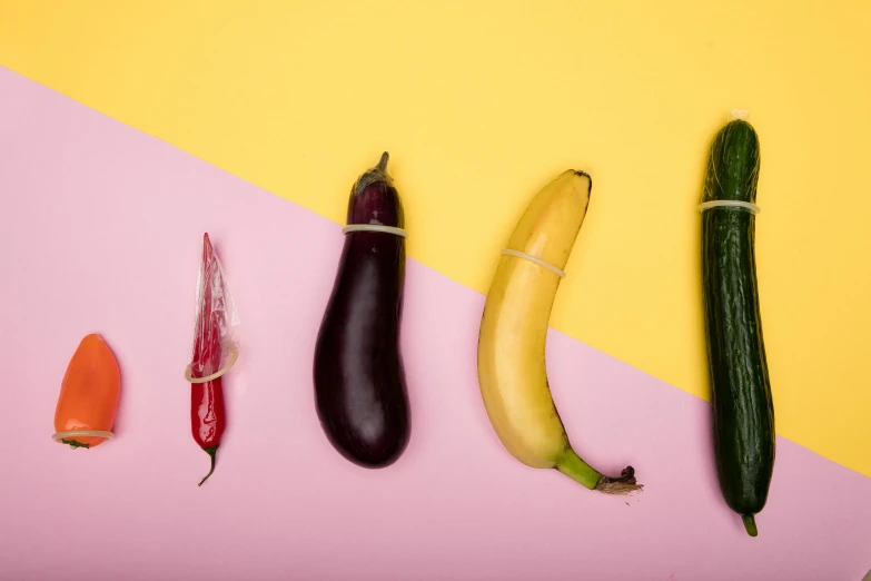 a group of vegetables sitting on top of a pink and yellow surface, sexuell, including a long tail, purple tubes, on grey background
