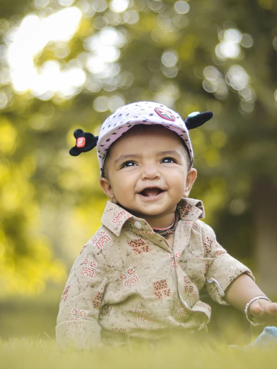 a baby sitting in the grass wearing a hat, a picture, by Basuki Abdullah, shutterstock contest winner, earing a shirt laughing, hindu, walking at the park, polka dot