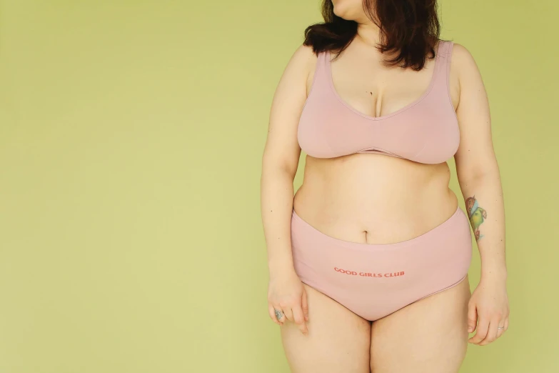 a woman in pink underwear standing in front of a green wall, trending on pexels, plasticien, obese ), on a pale background, nanae kawahara, wide frontal view
