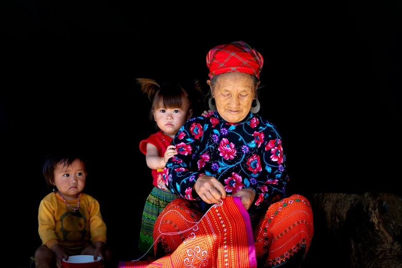 a woman and two children sitting next to each other, pexels contest winner, vietnamese woman, tribal clothing, thumbnail, an elderly