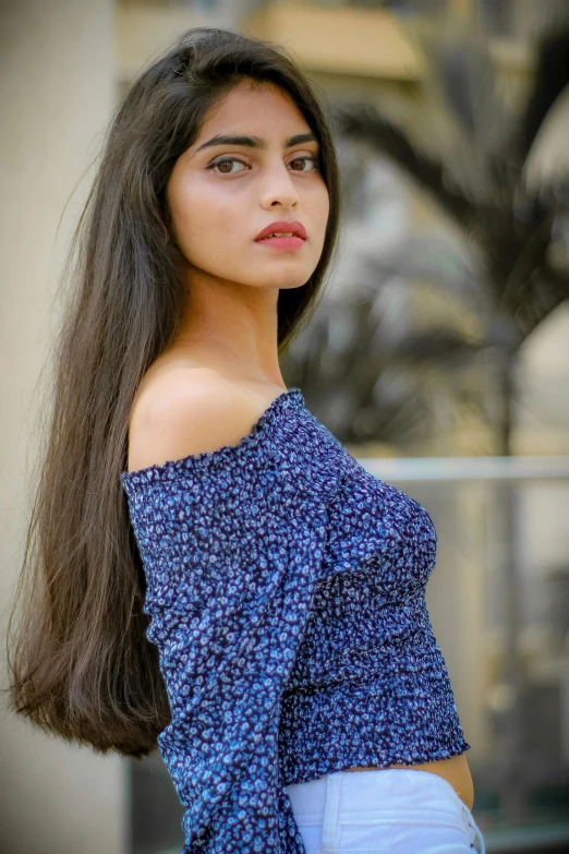 a beautiful young woman standing in front of a building, pexels contest winner, renaissance, dark blue long hair, indian super model, wearing a cute top, close up shot from the side