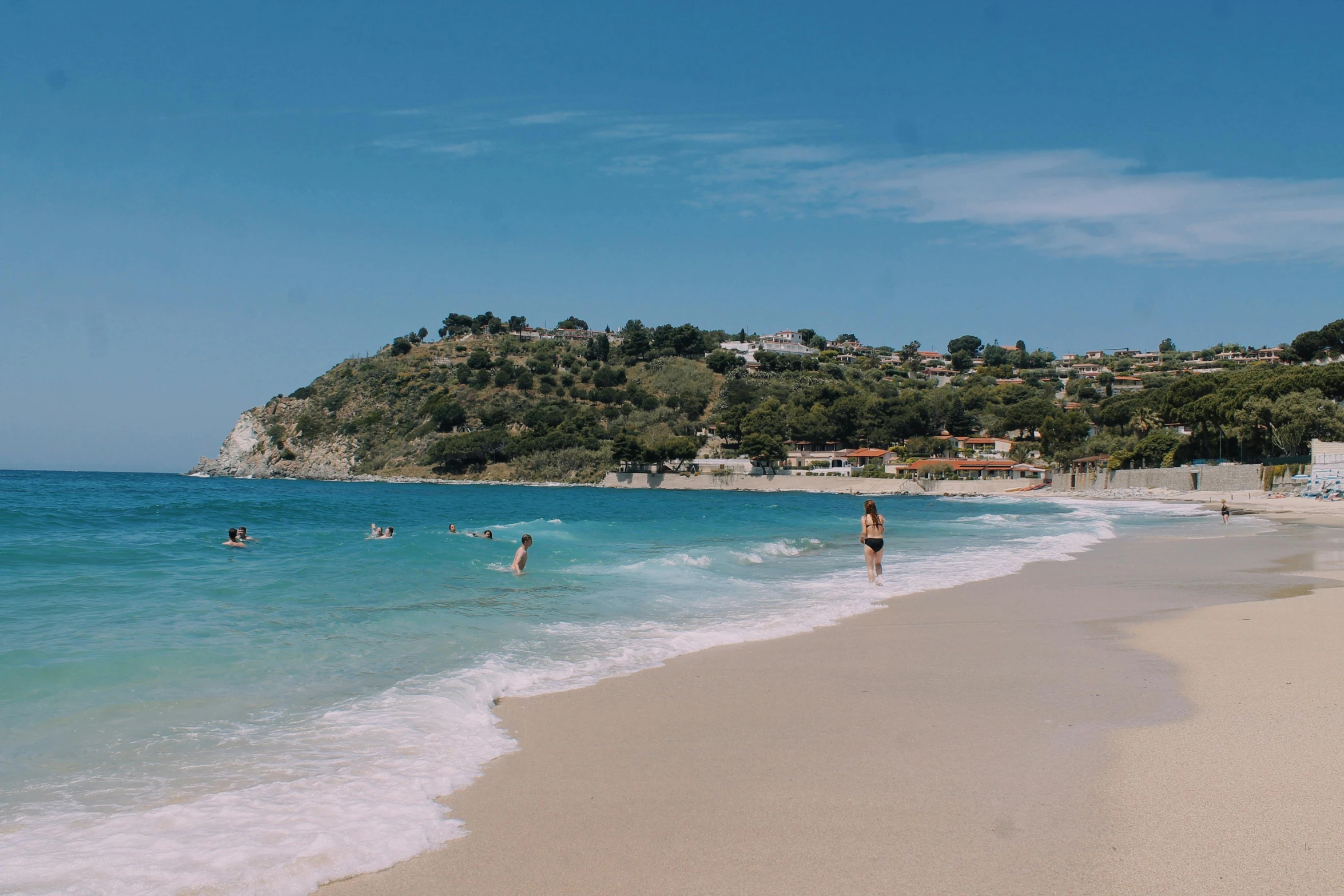 a group of people standing on top of a beach next to the ocean, crystal clear blue water, alexandros pyromallis, square, blonde