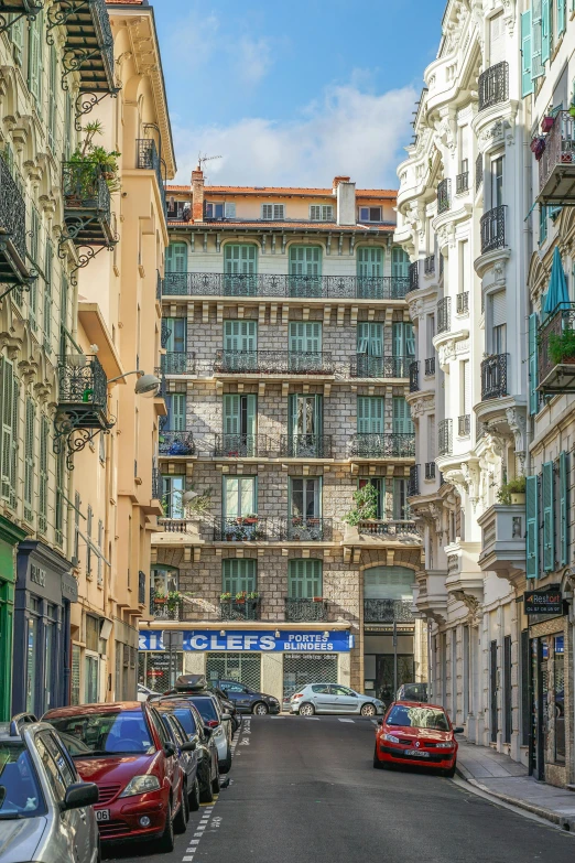 a narrow street lined with parked cars next to tall buildings, art nouveau, nice, french village exterior, chaumet, balconies