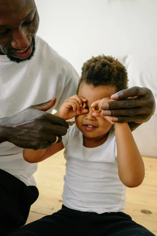 a man and a little boy sitting on the floor, pexels contest winner, hands shielding face, eyeballs bulging, ebony, cheerios