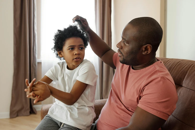 a man and a little girl sitting on a couch, pexels, hurufiyya, thinning hair, black teenage boy, as well as scratches, father with child