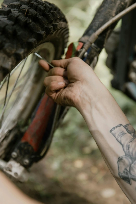 a close up of a person holding a bike tire, a tattoo, off - road, profile image, tools, celebrating