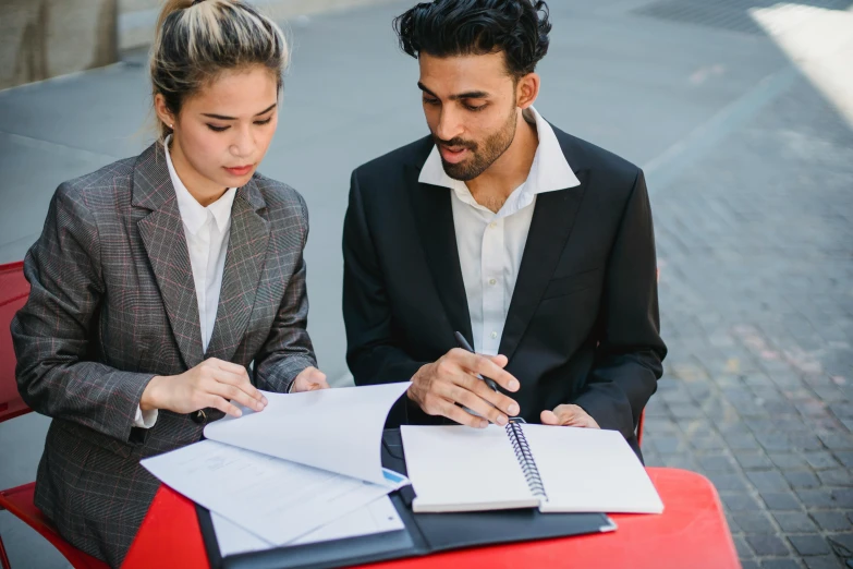 a man and a woman sitting at a table with notebooks, pexels contest winner, wearing a business suit, idealised, college students, te pae