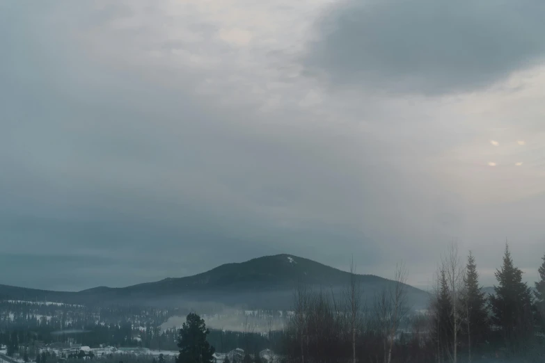 a man riding skis down a snow covered slope, a picture, inspired by Elsa Bleda, pexels contest winner, romanticism, under a gray foggy sky, distant town in valley and hills, “ aerial view of a mountain, overcast dawn
