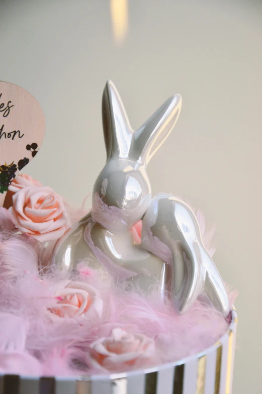 a white rabbit figurine sitting on top of a cake, inspired by Jeff Koons, detailed feathers, making love, shiny silver, medium close-up shot