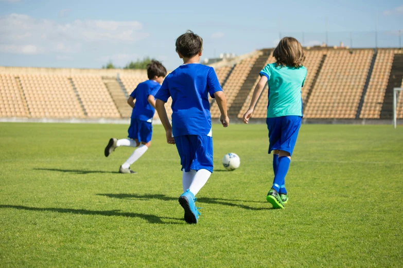 a group of young children playing a game of soccer, a picture, by Bernard Meninsky, shutterstock, incoherents, costa blanca, plain uniform sky at the back, stadium, screensaver