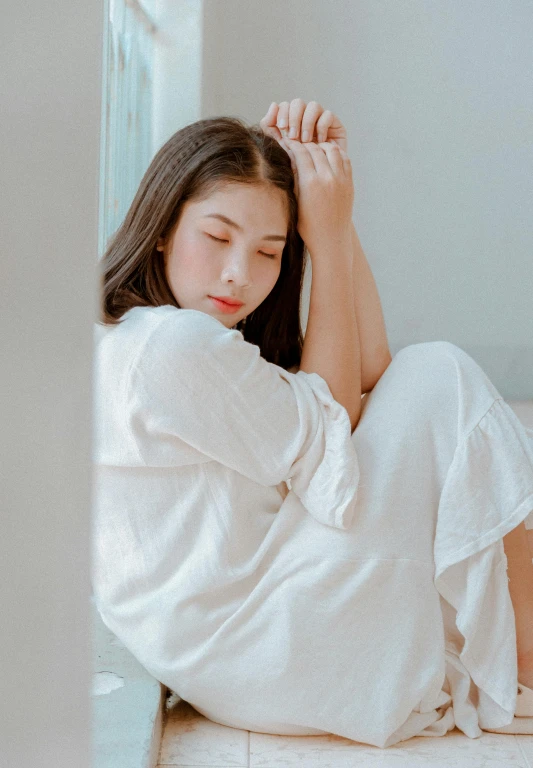 a woman sitting on the floor in a white robe, by Tan Ting-pho, pexels contest winner, aestheticism, tired face, long shirt, cindy avelino, wearing pajamas