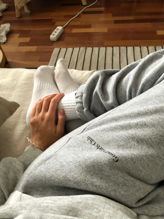 a woman laying on top of a bed next to a dog, by Christen Dalsgaard, instagram, happening, light grey hoodie opened, thighs close up, trending on r/streetwear, on a couch