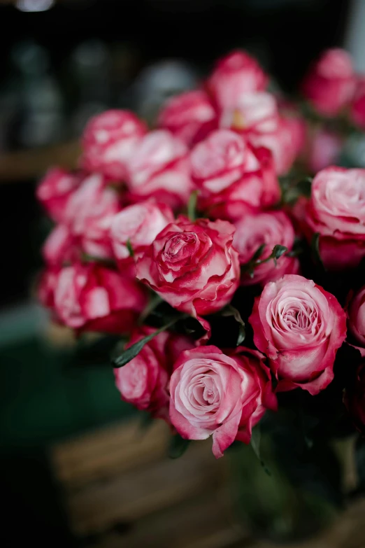 a vase filled with pink roses sitting on top of a table, by Robbie Trevino, trending on unsplash, close up head shot, reds, with a soft, covered in