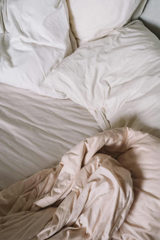 an unmade bed with white sheets and pillows, an album cover, inspired by Elsa Bleda, unsplash, ignant, birdseye view, faded pink, morning detail