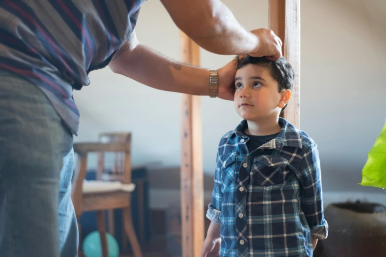 a man combing a young boy's hair, pexels contest winner, macguire is a tall, at home, wearing a school uniform, “ iron bark