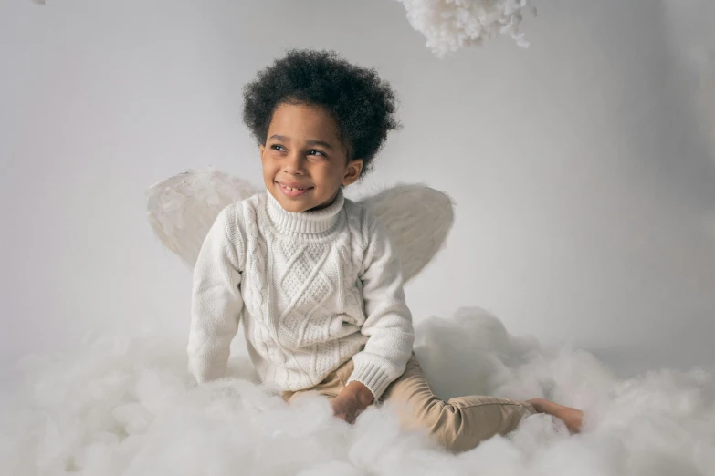 a little boy sitting on top of a pile of fluffy white clouds, inspired by George Barker, pexels contest winner, black angel wings, photoshoot for skincare brand, wearing a white sweater, while smiling for a photograph