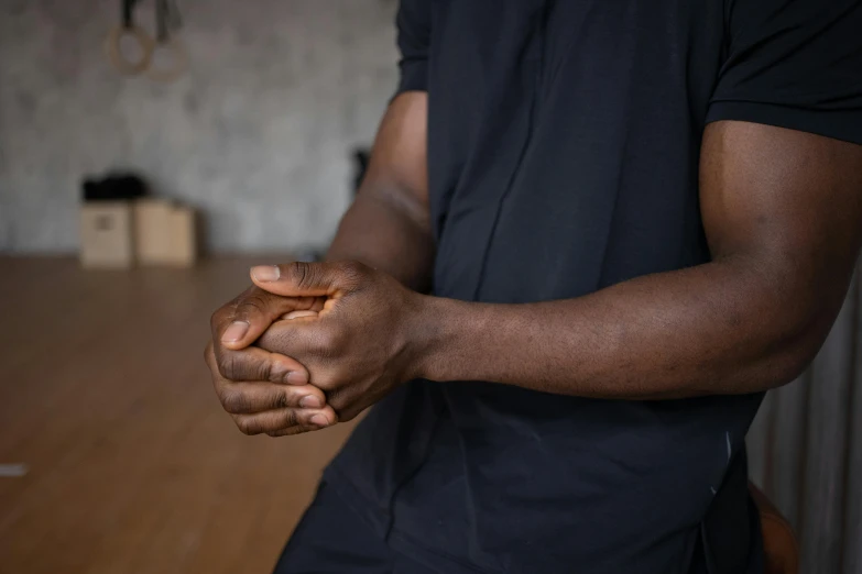 a close up of a person holding something in their hands, black man, recovering from pain, wearing a black shirt, relaxed posture