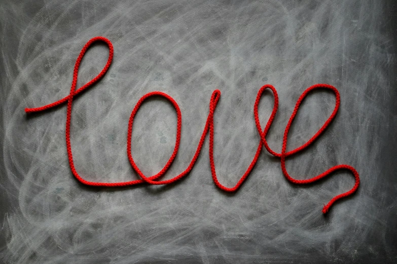 a chalkboard with the word love written on it, pexels, red wires wrap around, red selective coloring, macrame, on grey background