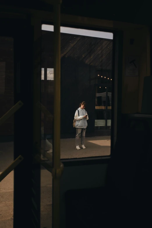 a man standing in front of a window in a dark room, inspired by Elsa Bleda, pexels contest winner, hyperrealism, in front of ramen shop, a woman walking, standing in an arena, looking in mirror