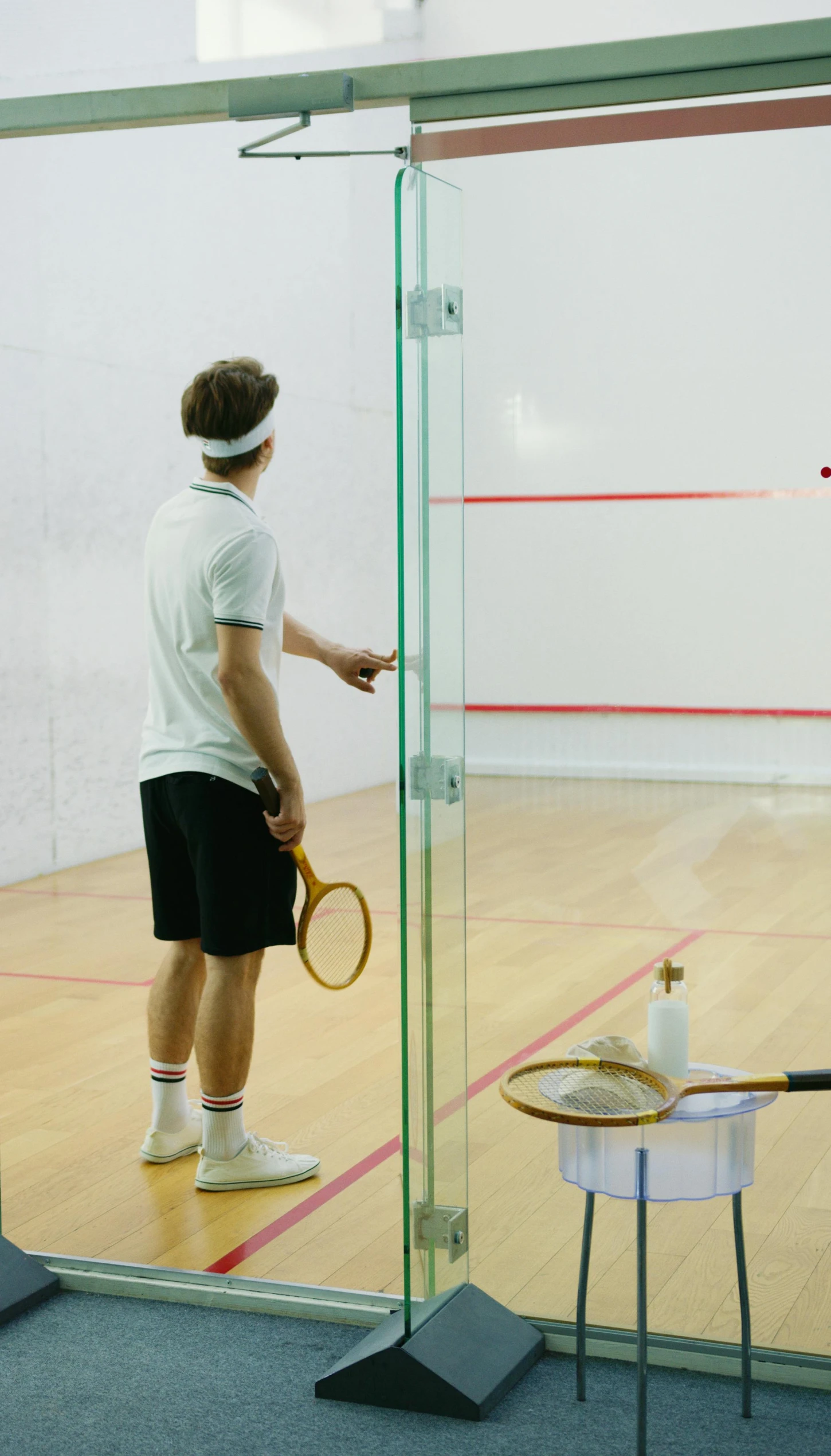 a man standing in front of a glass door holding a racquet, by Robert Medley, shutterstock, playing games, 15081959 21121991 01012000 4k, instagram post, locker room