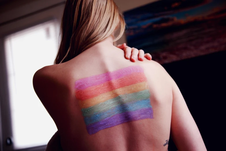 a woman with a rainbow painted on her back, a tattoo, trending on pexels, synchromism, big symmetrical scar features, light toned, rectangle, lesbian art
