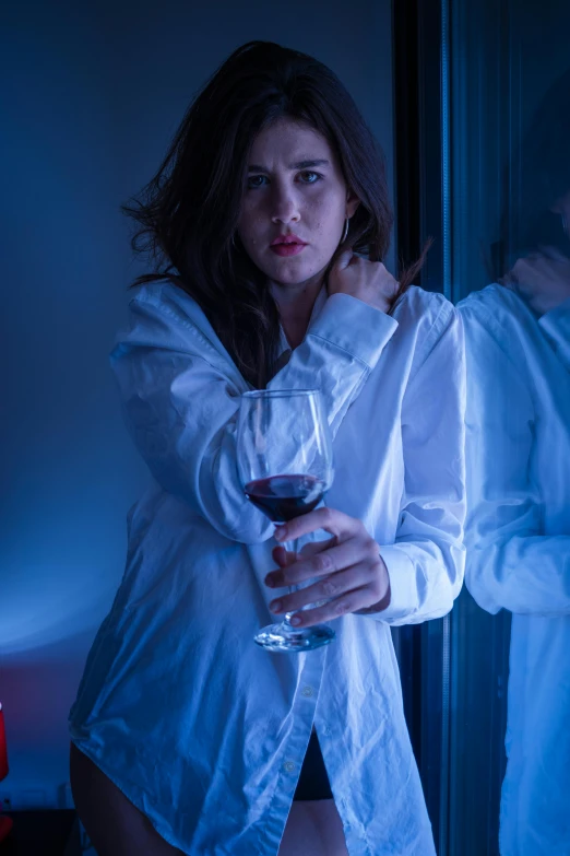 a woman standing next to a man holding a glass of wine, inspired by Nan Goldin, renaissance, film still from a horror movie, wearing white pajamas, blue mood, ( ( theatrical ) )