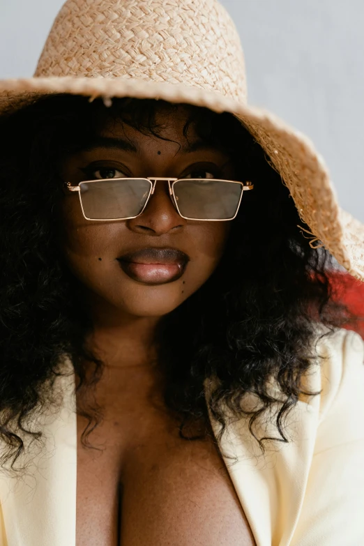 a close up of a person wearing a hat and glasses, by Winona Nelson, trending on pexels, afrofuturism, alluring plus sized model, square glasses, gold hour light, muted brown