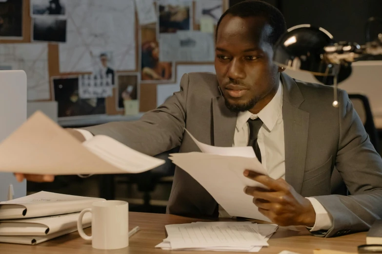 a man sitting at a desk in front of a computer, pexels contest winner, private press, adut akech, piles of paperwork, official screenshot, youtube thumbnail
