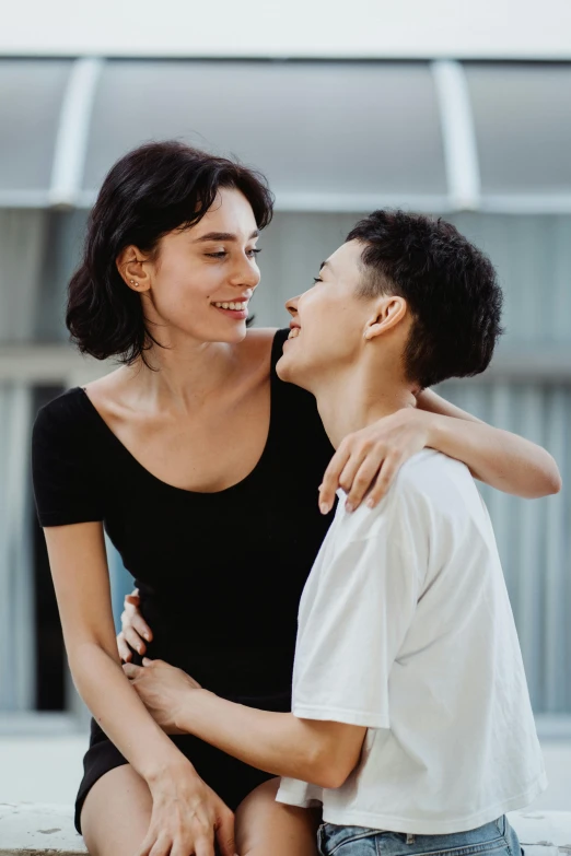 a woman sitting next to a boy on a bench, by Nina Hamnett, trending on pexels, antipodeans, lesbian embrace, couple dancing, maggie cheung, androgynous face