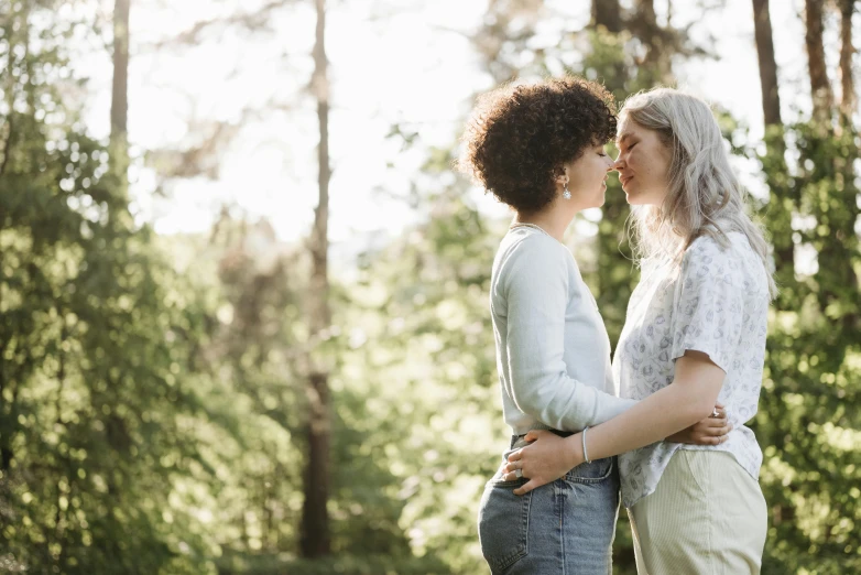 two women standing next to each other in the woods, trending on pexels, romanticism, lesbian kiss, diverse, high quality product image”, happy couple