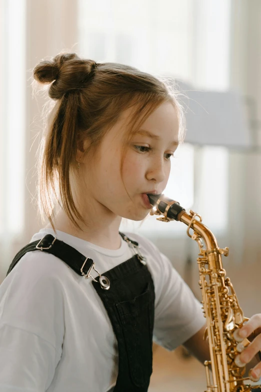 a little girl that is playing a saxophone, pexels contest winner, focused on her neck, student, next gen, no cropping