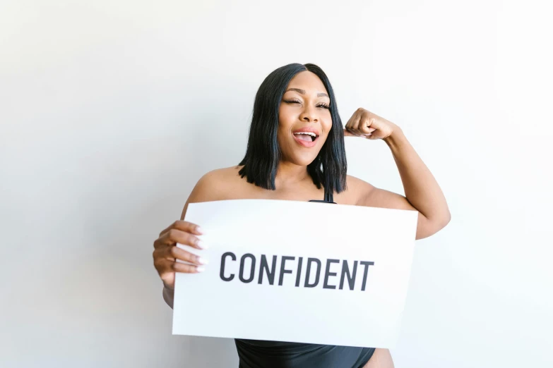 a woman holding a sign that says confident, pexels contest winner, curvy body, african american woman, profile image, frontal pose