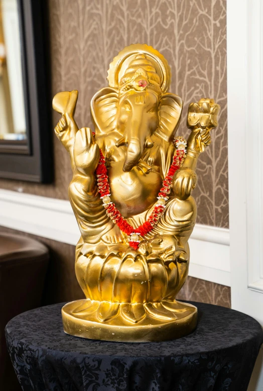 a gold statue sitting on top of a black table, vinayak, gold and red accents, delightful surroundings, premium