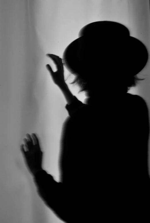 a black and white photo of a woman in a hat, inspired by Lillian Bassman, flickr, eerie person silhouette, crying and reaching with her arm, ( ( ( in a dark, photo pinterest