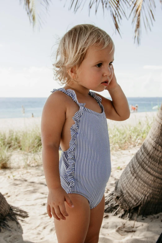 a little girl standing on top of a sandy beach, blue and white, ‘luca’, sturdy body, frill