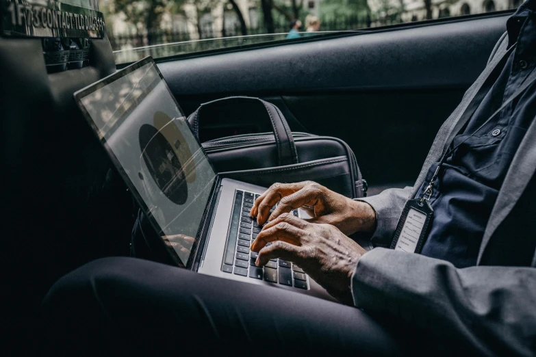 a man sitting in a car using a laptop computer, by Carey Morris, pexels contest winner, impeccably dressed, handwritten, thumbnail, multiple stories