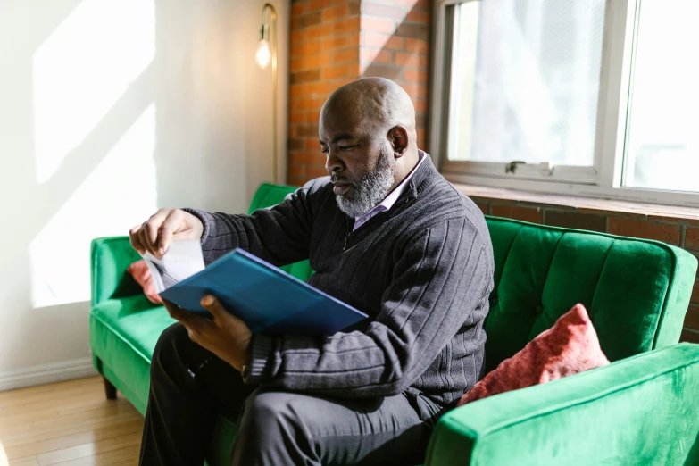 a man sitting on a green couch reading a book, older male, riyahd cassiem, thumbnail, teaching