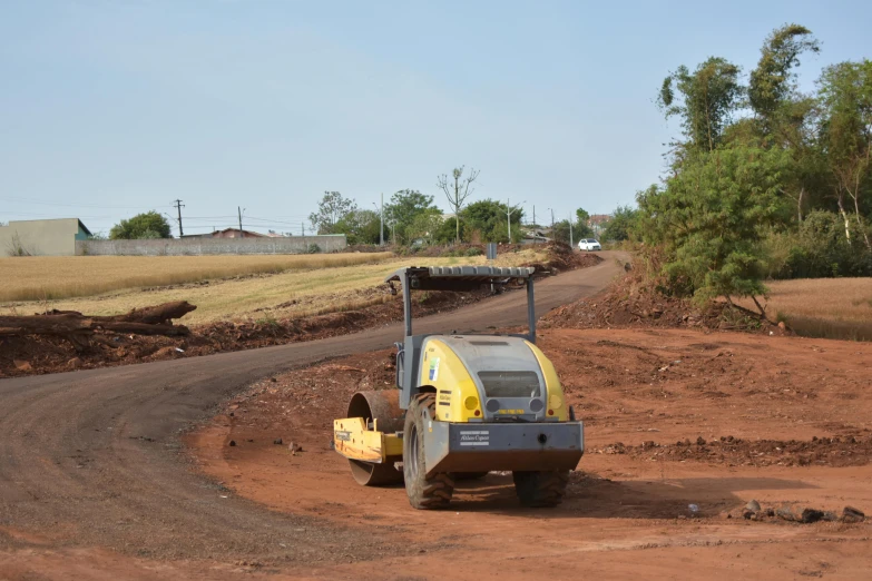 a yellow road roller driving down a dirt road, by Willian Murai, samikshavad, são paulo, curvy build, slide show, te pae