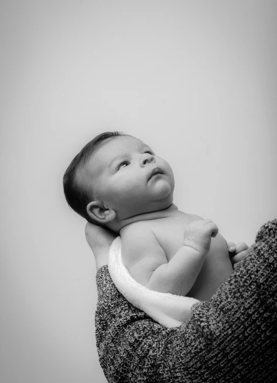 a woman holding a baby in her arms, a black and white photo, pexels contest winner, symbolism, a handsome, looking upwards, high quality upload, studio photoshoot