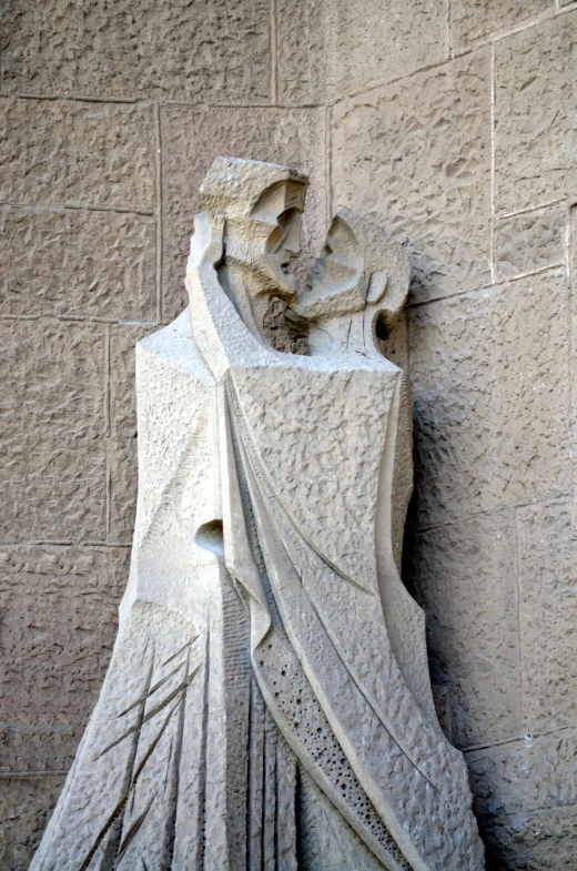 a statue that is on the side of a building, by Gaudi, jesus hugging a woman, sparse detail, ( ( ( art deco ) ) ), folded