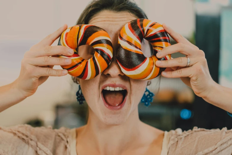 a woman holding two donuts over her eyes, pexels contest winner, swirly, 🦩🪐🐞👩🏻🦳, recipe, everything is made of candy