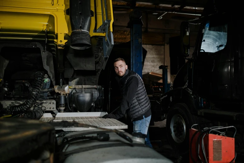 a man standing next to a truck in a garage, by Matthias Stom, pexels contest winner, arbeitsrat für kunst, heavy machinery, avatar image, sean mcloughlin, profile photo