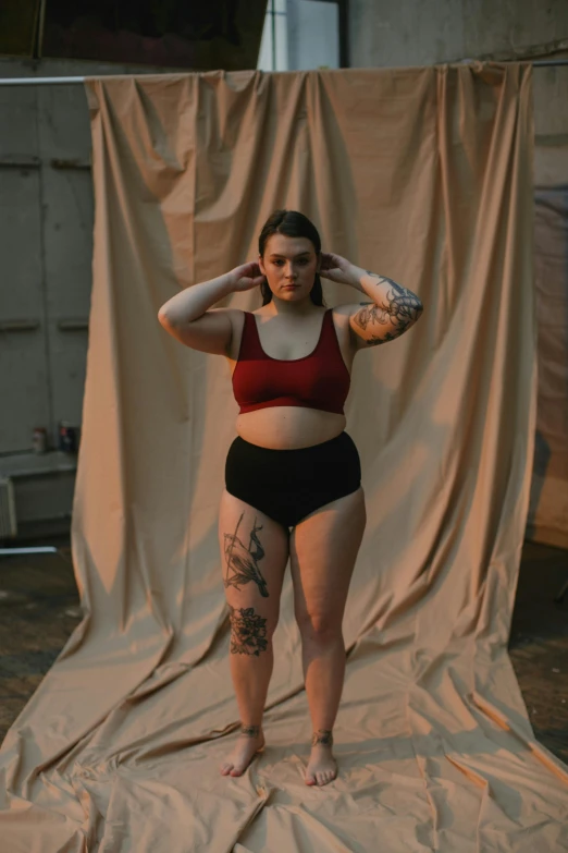 a woman posing for a picture in a studio, an album cover, inspired by Elsa Bleda, pexels contest winner, renaissance, croptop and shorts, overweight, tattooed skin, cropped red yoga short