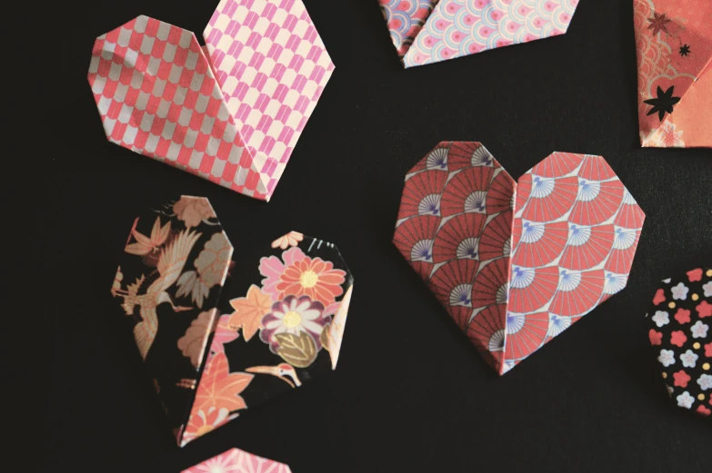 a bunch of origami paper hearts on a table, by Andrée Ruellan, sōsaku hanga, ornate designs on desk, cards, lumine, thumbnail