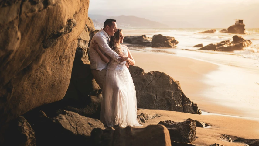 a man and woman standing next to each other on a beach, by Lee Loughridge, pexels contest winner, renaissance, flowy hair standing on a rock, wellington, romantic themed, white
