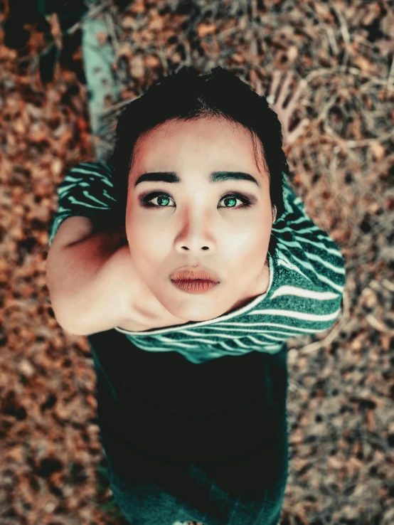 a woman with green eyes looking up at the camera, a picture, inspired by Ren Hang, trending on pexels, asian human, outdoor photo, high angle shot, desaturated