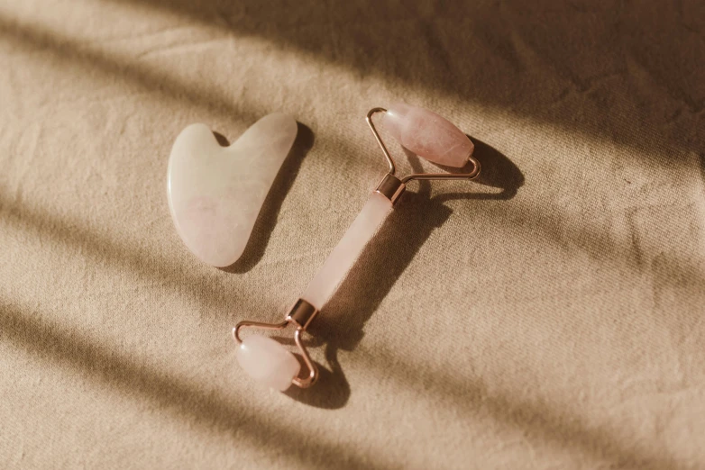 a pair of earrings sitting on top of a table, an abstract sculpture, trending on pexels, bandages, rose quartz, tools, lying down